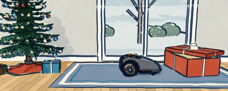 Christmas morning: a grey robot mower with a bow on it stands by its opened box, the tree at the left. Through the glass door behind it the yard lies under snow.