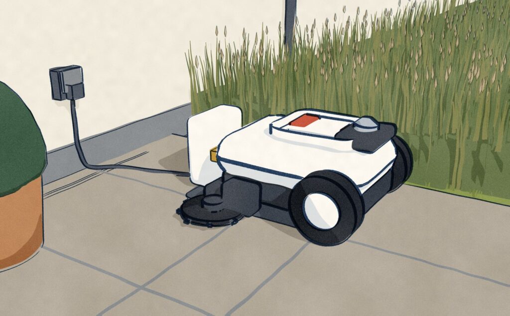 The Ecovacs GOAT A2000 sits docked on its charging station at the edge of a patio, its lead running along the house wall to an outdoor socket, the uncut lawn in front of it standing as tall as the mower.