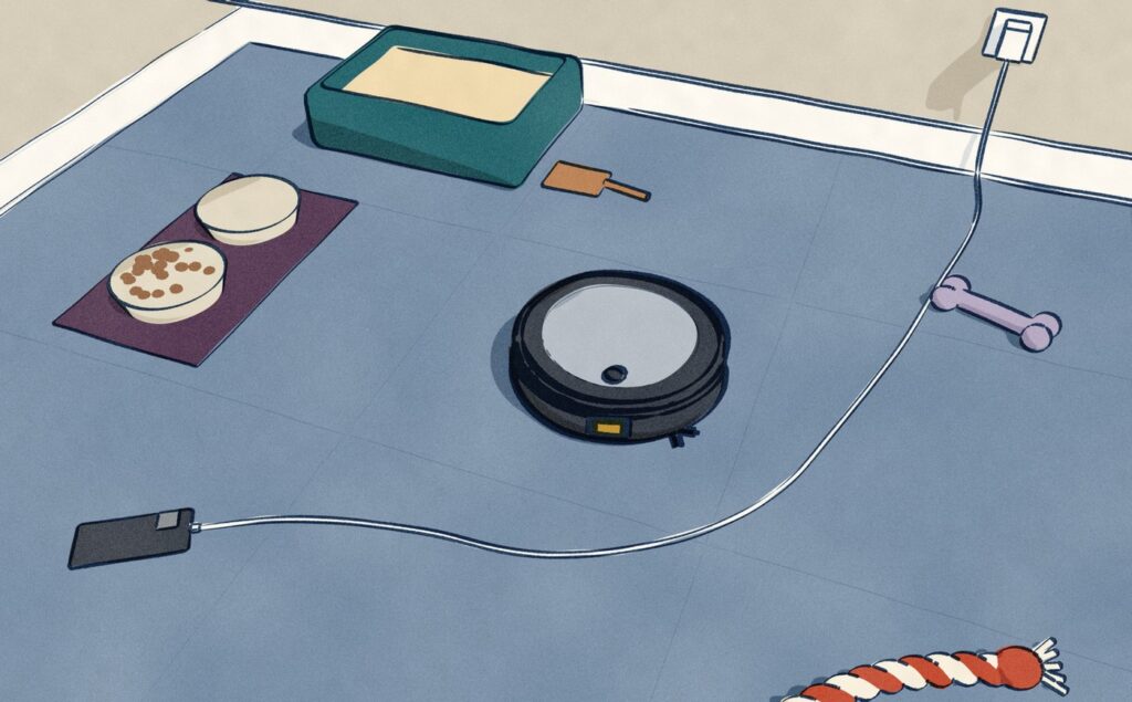 Seen from above in a utility corner, a black Roomba Combo j5+ with its silver lid heads toward a charger cord across the floor, a feeding mat with two bowls and a litter tray, the things iRobot says it will steer round.