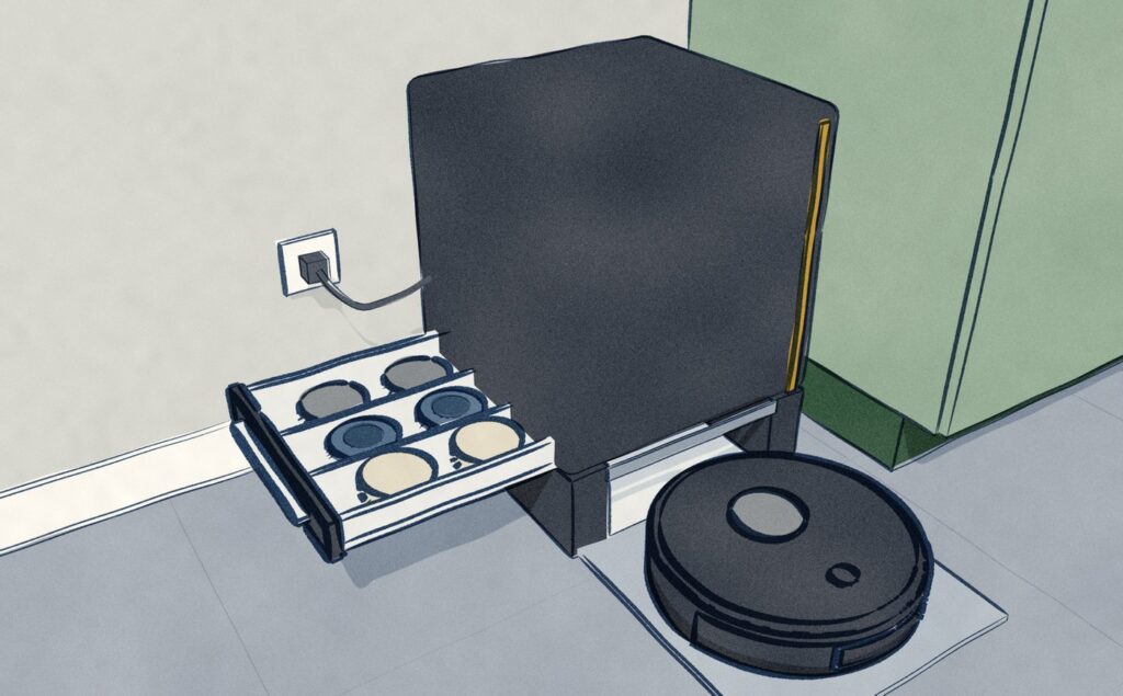 The black Dreame Matrix10 backs into its tall black dock beside the kitchen cabinets, the dock's side drawer pulled out to show three different kinds of mop pad in three rows: grey, blue and cream.