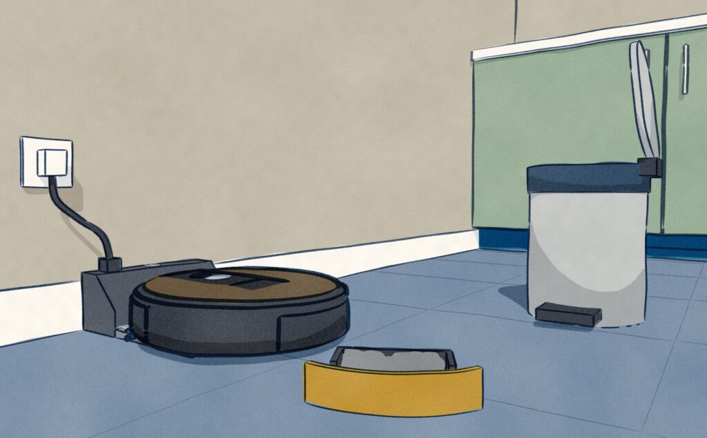 Close at a small dark charging base on a kitchen wall, a black Roomba sits with its dust bin pulled out of its back; the bin stands full of grey dust on the tiles beside an open kitchen bin.