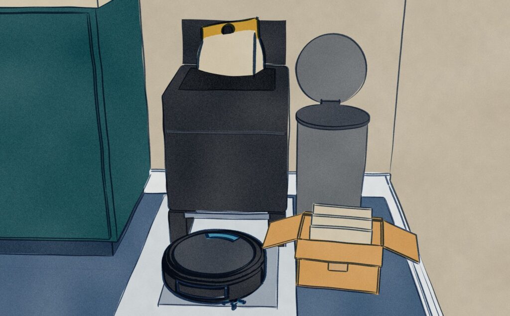 Close on a black robot vacuum dock in the corner of a utility room: its top lid stands open and the full dust bag leans half out of it, the black Lefant robot waits on the mat in front of its bay, and an opened box of spare bags sits on the floor by a pedal bin with its lid up.