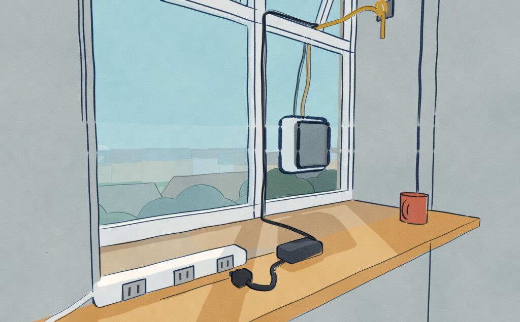 Inside the room: the window-cleaning robot's mains plug lies pulled out on the window board in front of a power strip, while through the glass the robot still holds on to the outside of the pane, its gold safety rope tied to an eye bolt in the window reveal, with treetops and roofs below.